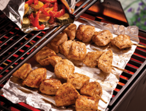 chicken skewers sitting on a piece of aluminum foil on the grill