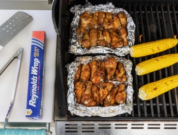 Cajun flavored chicken wings sitting on a sheet of foil on the grill