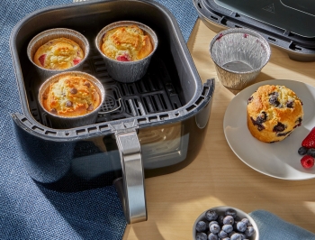 A variety of different flavor muffins in air fryer cups sitting in an air fryer basket