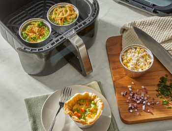 Custom side dishes in air fryer cups sitting alongside an air fryer basket
