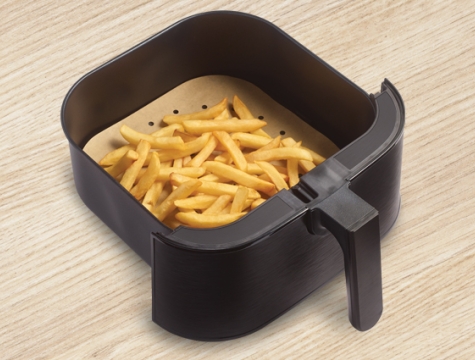 cooked french fries sitting on top of an air fryer liner in an air fryer basket