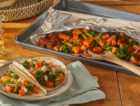 Spiced Sweet Potato and Kale Tacos sitting on a wood table alongside an open Reynolds grill bag with additional servings inside