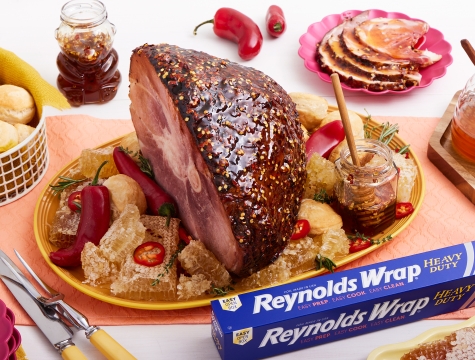 Cooked Ham with Hot Honey Glaze sitting on a platter alongside Reynolds Wrap Heavy Duty Foil