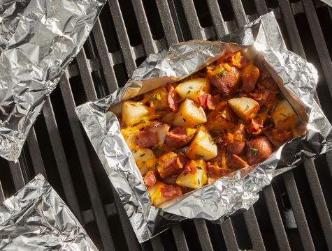 Roasted potatoes sitting in a foil packet on a hot grill