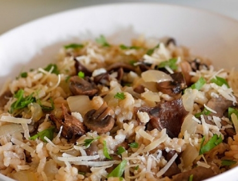 mushroom risotto in a white serving bowl topped with shredded parmesan cheese