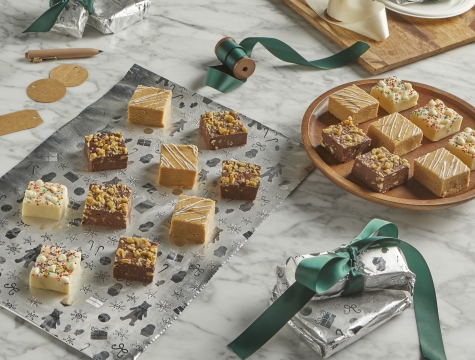 Squares of fudge sitting on a sheet of Reynolds Wrap Fun Foil alongside small packages of aluminum foil wrapped treats