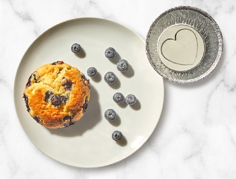 empty air fryer cup sitting alongside a plate with a blueberry muffin