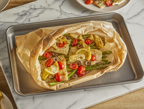 fish fillets and vegetables in a parchment cooking bag sitting on a baking sheet