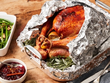 Turkey cooked using the foil wrap method with green beans and cranberry sauce nearby