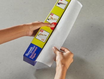 Person tucking the decurling panel into a parchment paper box and pressing the red tab