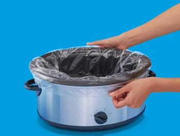 Person placing a slow cooker liner into an empty slow cooker