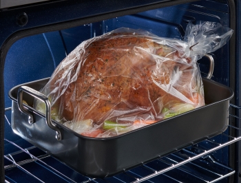Turkey in an oven bag sitting in a roasting pan in the oven