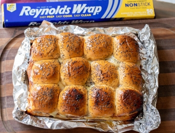 Ham and cheese sliders sitting on a piece of Reynolds Wrap non-stick foil