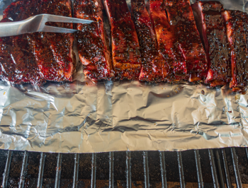 Sliced ribs sitting on aluminum foil on the grill