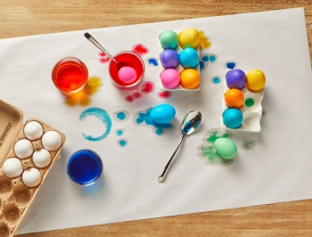 Easter eggs in the processed of being dyed on a table covered with a sheet of Reynolds Kitchens Countertop Prep Paper