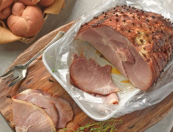 a whole cooked ham and a few slices on a wood tray