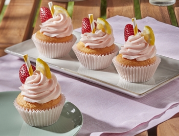 Pink lemonade cupcakes on a platter sitting on an outdoor table