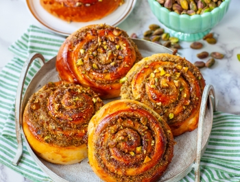 Pistachio Honey Cinnamon Rolls sitting on a plate on a kitchen counter